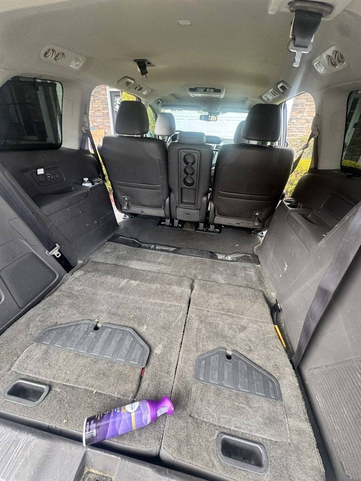 Minivan cargo area before detailing — soiled carpet with debris and scattered items