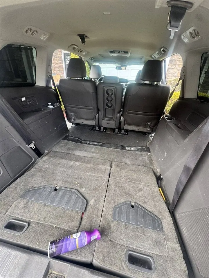 Minivan cargo area before detailing — soiled carpet with debris and scattered items